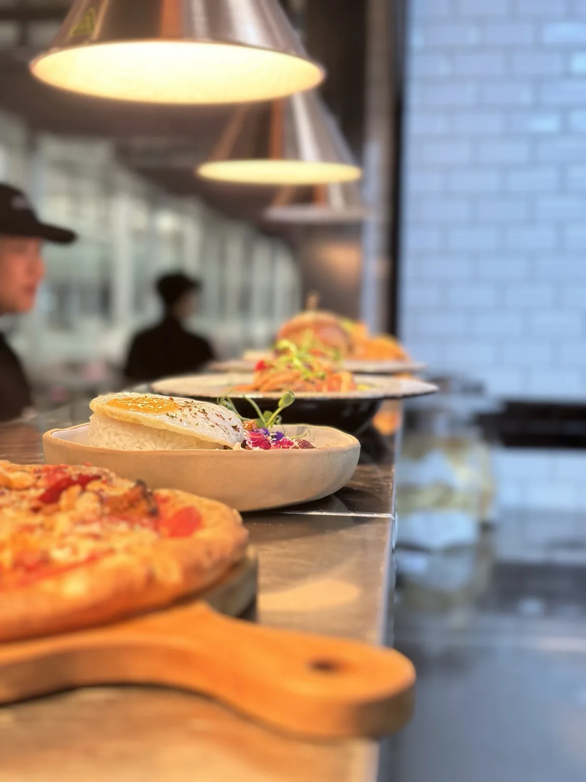 Freshly plated food under copper lamps at the Six Nine kitchen pass